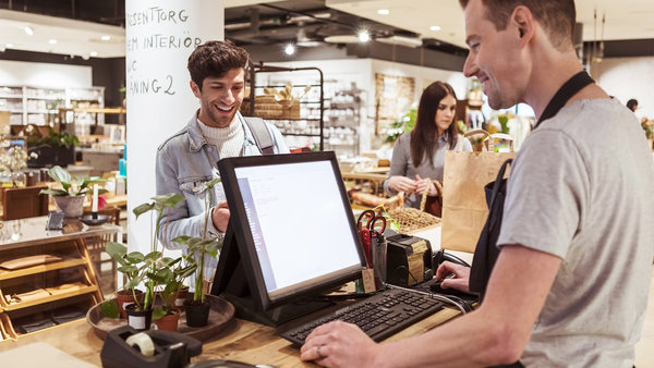 cashier using computer while talking to-smiling customer