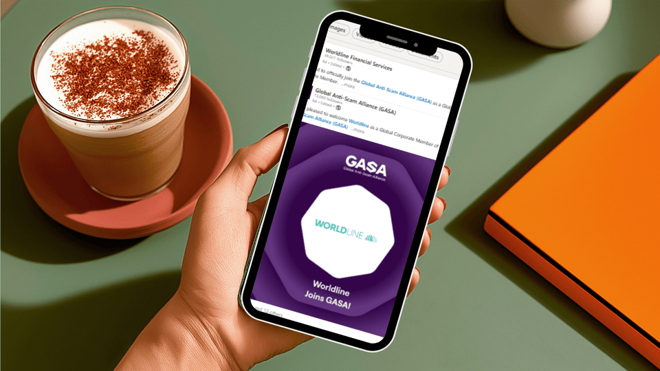 person holding a mobile phone next to a capuccino