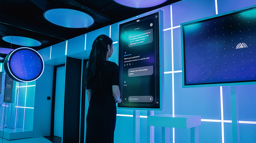 A woman looking at a large screen displaying an AI prompt