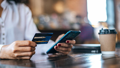 woman using a mobile whilst holding a credit card
