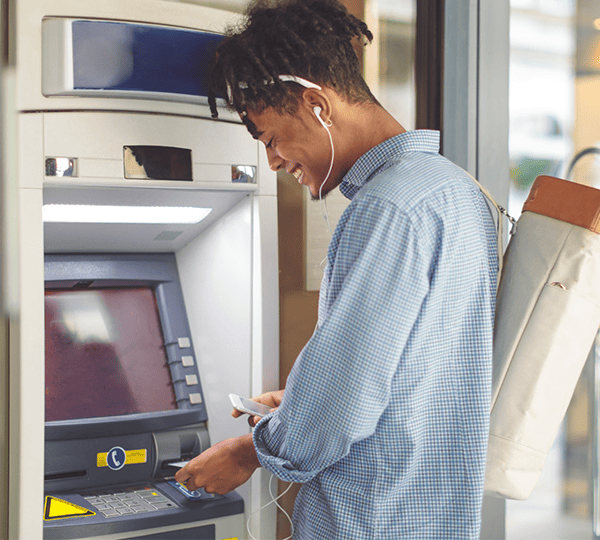 woman using contactless payment smartphone to pay for shopping at self checkout kiosk for atm management solutions