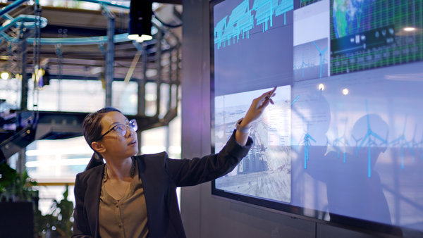 A woman presenting data on a huge screen