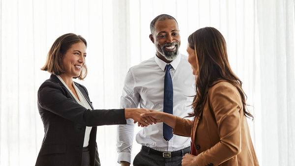 businesswomen shaking hands by coworker