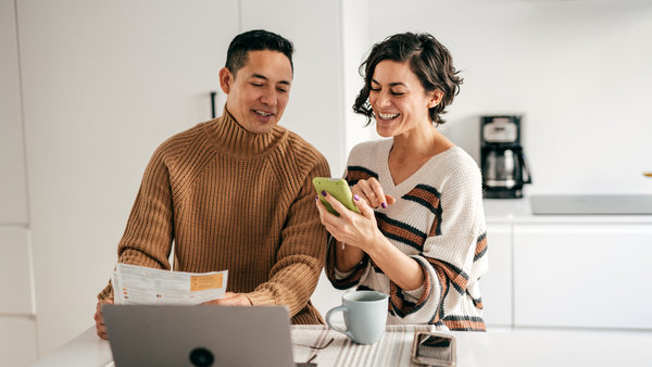 couple in the kitchen looking at phone using instant settlement payment gateway