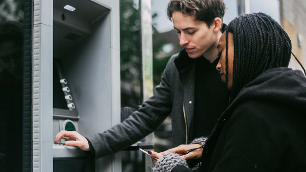 couple using an ATM machine and mobile phone