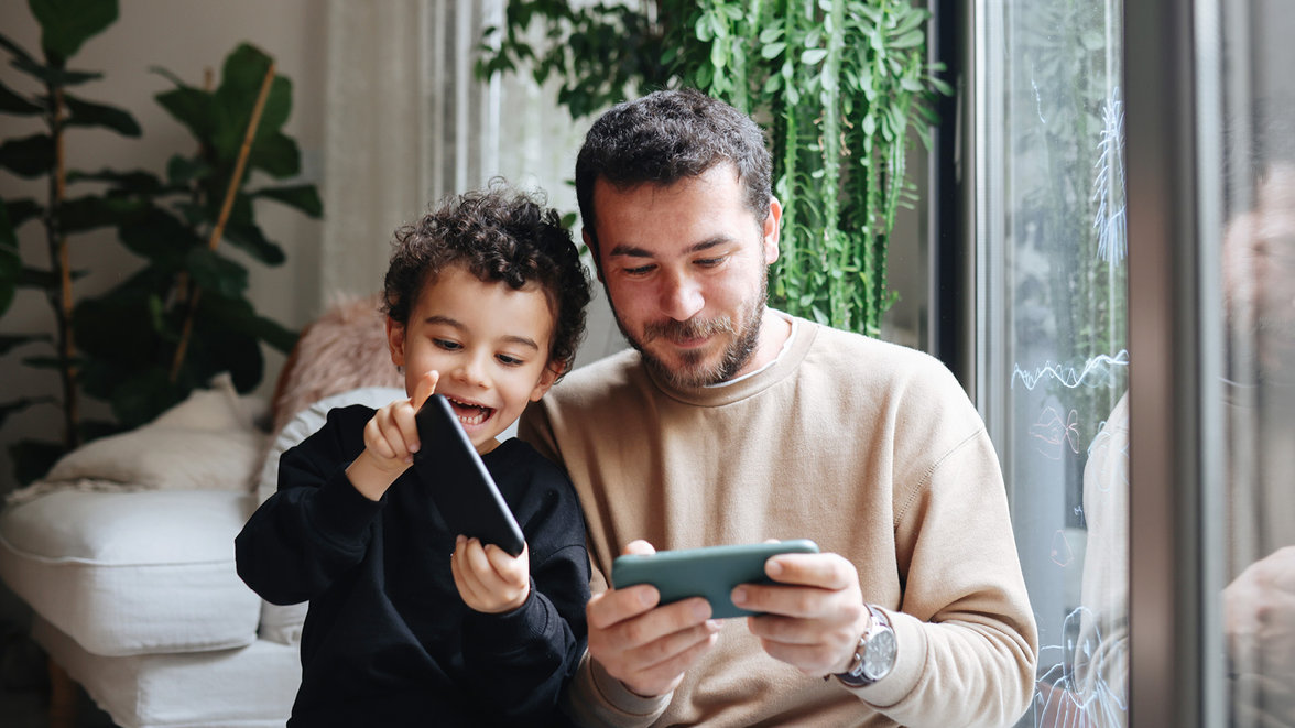 father and son playing videogames on smartphone for digital goods and services