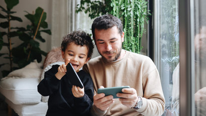 father and son playing videogames on smartphone