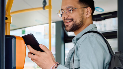 A woman sticking her phone to a public transportation ticket machine while on the bus.