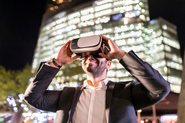 Man smiling and using VR glasses in the street at night