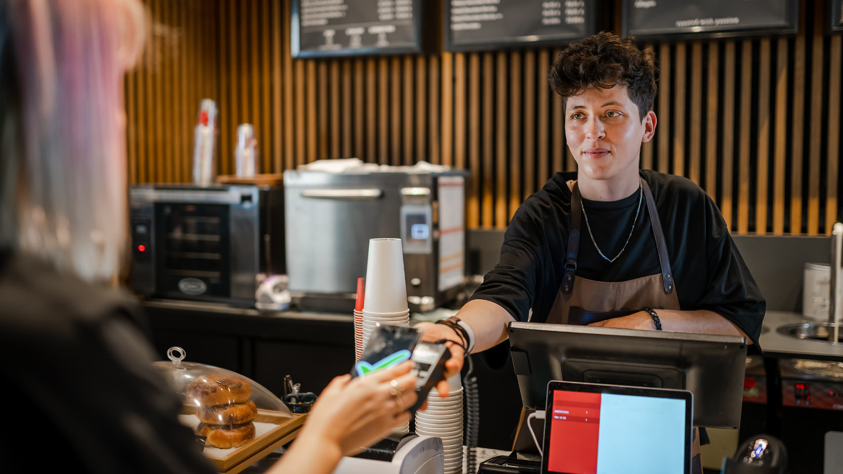 Smiling barista taking fast and easy payment in the coffee shop