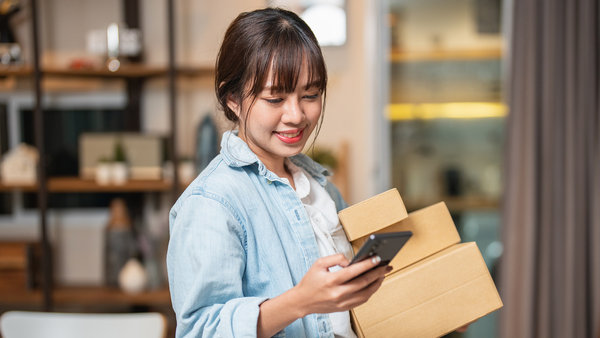 Jeune femme asiatique suivant la livraison d'un colis provenant d’une boutique en ligne à l'aide d'un portable.
