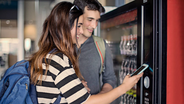 young couple paying with mobile phone the soft drink at vending machine