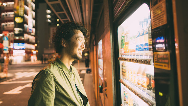 young japanese man buys drink from the machine using vending machine payment system
