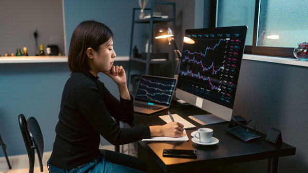 Young woman doing cryptocurrency business trading on her computer at home at night