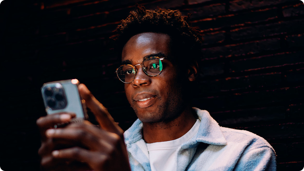 Man wearing round glasses using his smartphone
