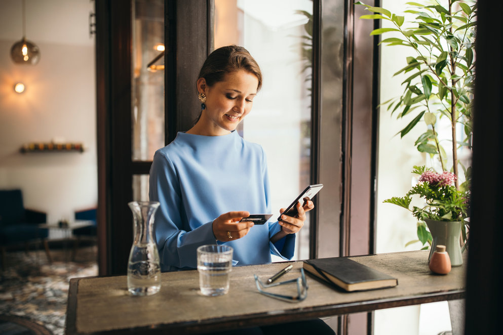 woman using mobile and card to complete payment