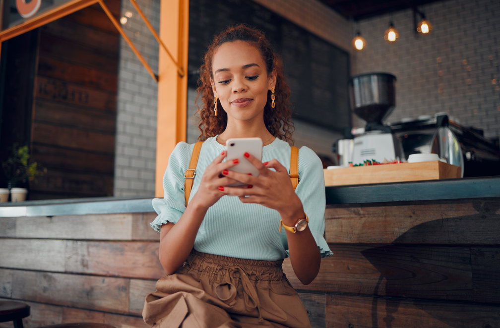 Woman holding smartphone in a coffee shop