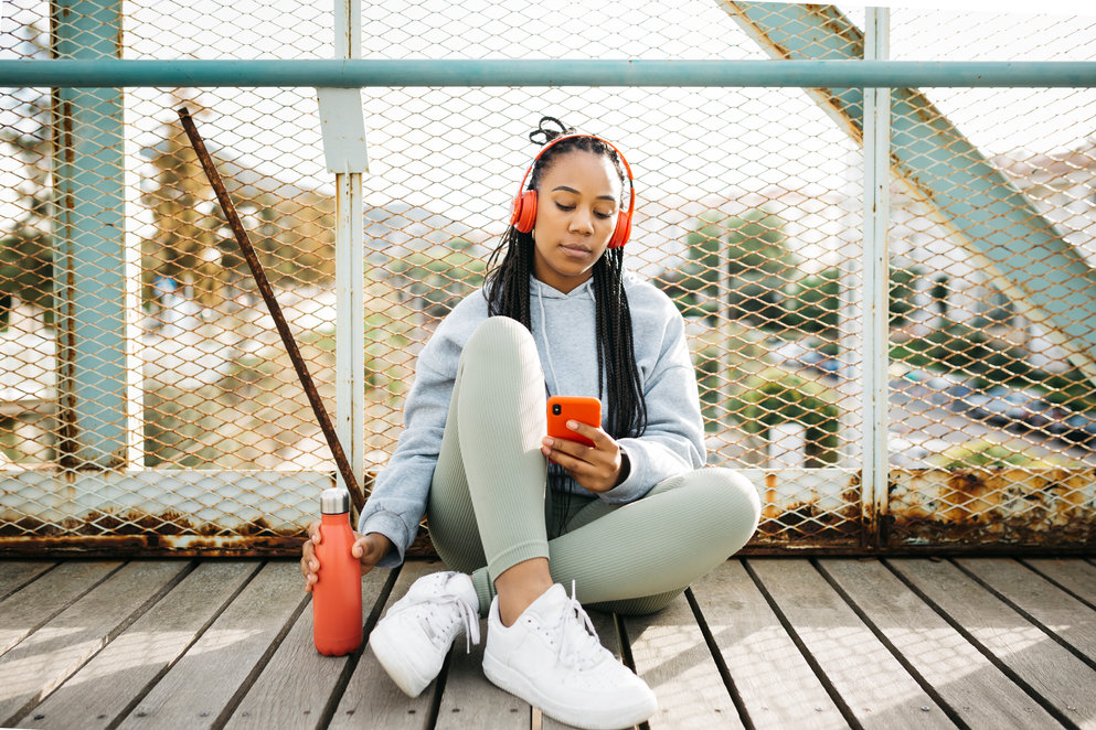 Woman sitting on a urban bridge using smartphone