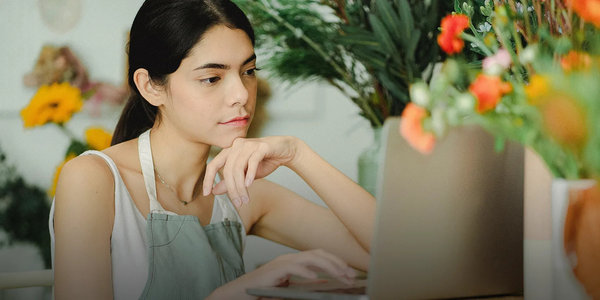 Kvindeder arbejder i blomsterbutik kigger på sin computer