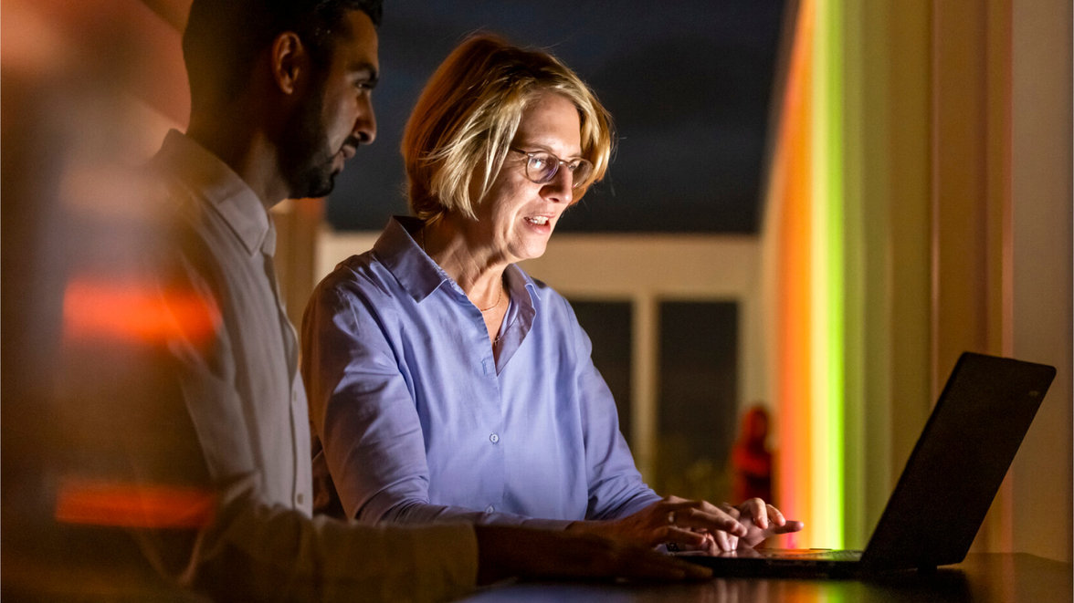 People looking at laptop in dark room