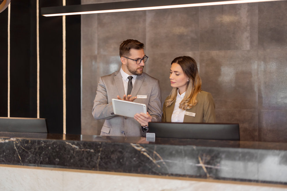 A man and a woman at the office both looking at a tablet.