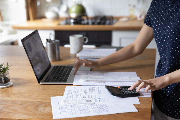 person on table making calculations and checking laptop