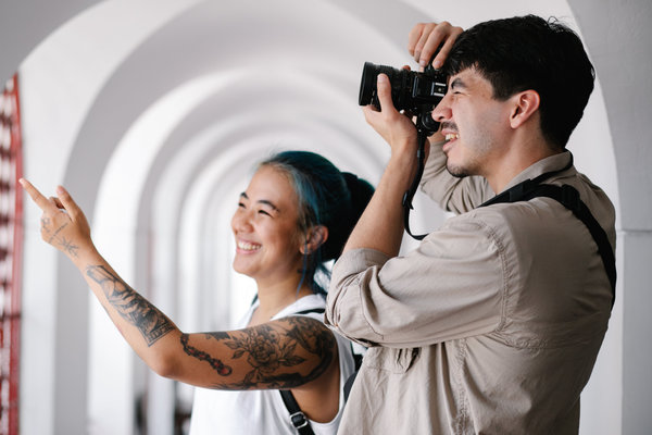 A man taking a picture of something a woman standing to him is pointing