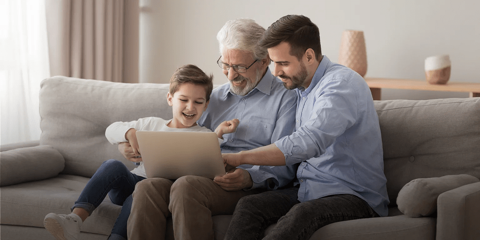 a child, his father and grandfather sitting watching a tablet